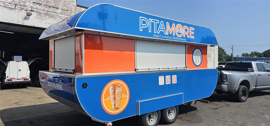 PitaMore blue Mediterranean food trailer with roll-up serving windows and menu graphics